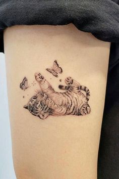 a small tiger and butterfly tattoo on the back of a woman's thigh, with butterflies