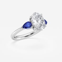 an oval diamond and blue sapphire engagement ring with two pear shaped diamonds on the side