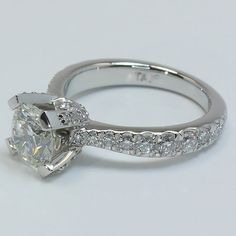 a close up view of a diamond engagement ring on a white surface with diamonds surrounding it