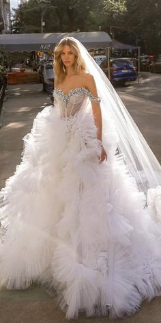 a woman in a white wedding dress is walking down the street