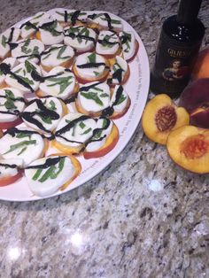 a plate full of appetizers next to some peaches and a bottle of wine