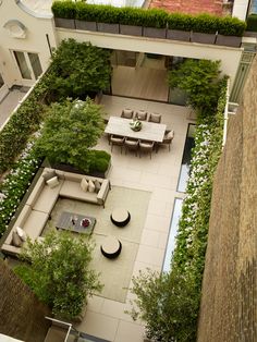 an aerial view of a courtyard with tables and chairs in the center, surrounded by greenery