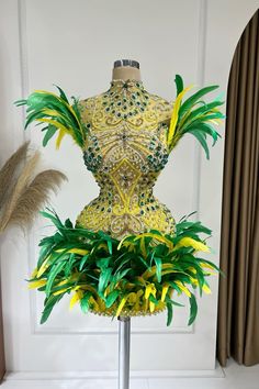 a mannequin is adorned with green and yellow feathers