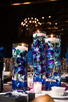 two vases with flowers and candles on a table