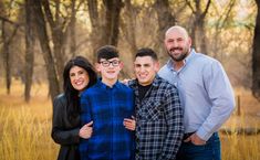 a family poses for a photo in the woods with tall grass and trees behind them