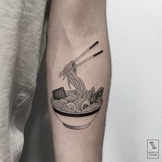 a black and white photo of a person with a tattoo on their arm holding a bowl of noodles