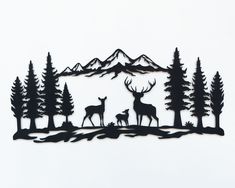 a metal wall hanging with deer and trees in front of a mountain range filled with pine trees