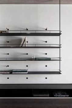 a shelf with several books on it in front of a wall that has two shelves