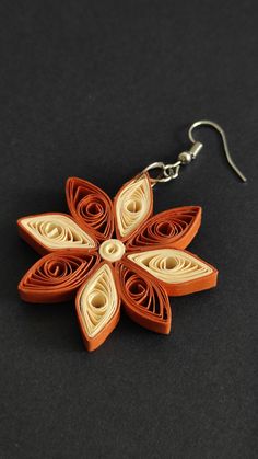 an origami flower is hanging from a pair of earrings