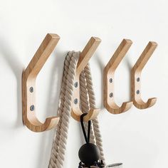 there are three wooden hooks on the wall with ropes attached to them, and one hook is holding a cord