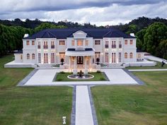 an aerial view of a large white house in the middle of a grassy area with trees