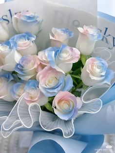 a bouquet of white and pink roses in a blue ribbon