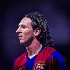 a man with long black hair wearing a red and blue soccer jersey looking off to the side