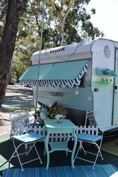 an rv is parked next to some chairs and tables