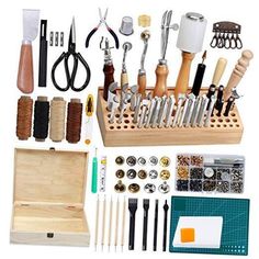 an assortment of crafting tools and accessories in a wooden box on a white background