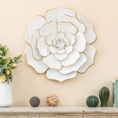 a large white flower is on the wall next to some vases and other items