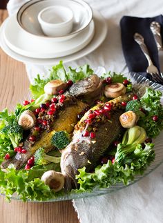 a plate with fish, vegetables and mushrooms on it next to a fork and knife