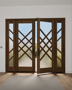 an open wooden door in a white room with wood flooring and glass panels on the doors