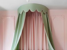 a canopy bed with pink walls and green curtains