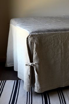 a bed with a white cover on top of it next to a striped rug and wall