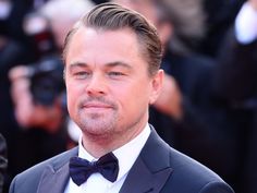 a close up of a person wearing a suit and bow tie with cameras in the background