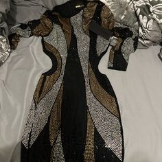 a black and gold dress laying on top of a bed