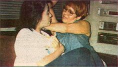 two women hugging each other while sitting on a couch in front of a television set