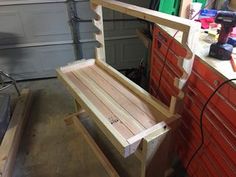 a wooden bench sitting in front of a garage door next to a tool box and other tools