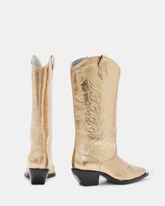 Staying true to their vintage roots, the Dolly Western Boots are made from metallic leather with delicate stitchwork all-over. The authentic shape is slightly chunkier in the heel for a modern spin. The perfect boot to pair with floral prints, oversized tees and mini skirts - make them your new go-to.   This style fits true to size Pointed toe Pull on Detailed stitchwork Comfortable fixed cushion insole Gold Leather Boots With Almond Toe, Gold Almond Toe Leather Boots, Gold Snip Toe Boots For Fall, Gold Leather Western Boots, Western Gold Heeled Boots, Gold Western Boots With Almond Toe, Western Style Gold Heeled Boots, Oversized Tees, Leather Western Boots