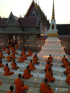 a group of people sitting in front of a large white pyramid with candles on it