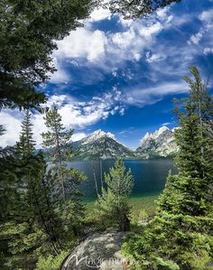 the mountains are in the distance and there is a lake below them with trees on both sides