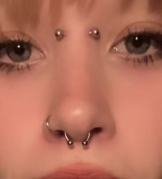 a woman with piercings on her nose and nose ring in front of her face