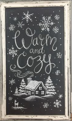 a chalkboard with the words warm and cozy written in white on it, surrounded by snowflakes