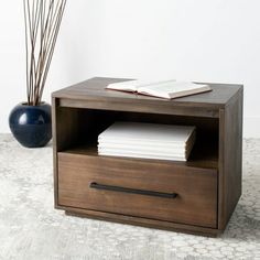 a book is sitting on top of a wooden box next to a vase with flowers