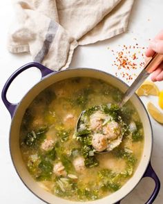 a pot filled with meatballs and vegetables next to lemon wedges on a table