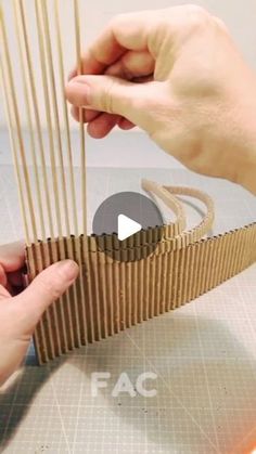 two hands are working on an object made out of cardboard and wood sticks with tape