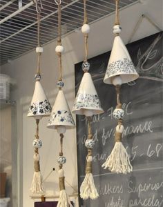 several hanging bells with tassels attached to them in front of a chalkboard