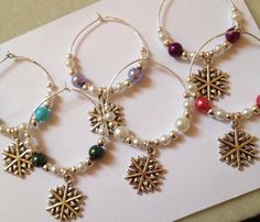 three pairs of hoop earrings with snowflakes and pearls hanging from them on a piece of paper