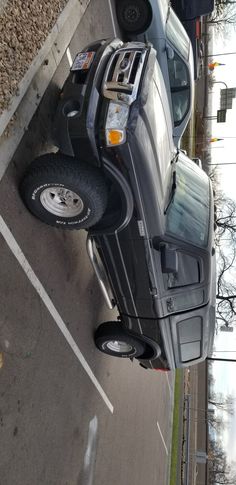 there is a truck parked on the side of the road next to another car that has it's door open