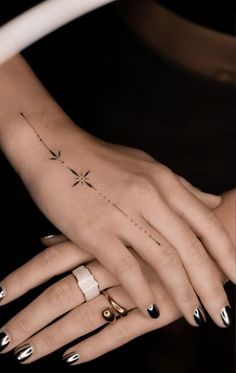 two hands holding each other with tattoos on their fingers and one has a star tattoo on it