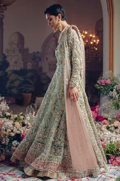 a woman in a long dress standing on a flower covered floor with flowers around her