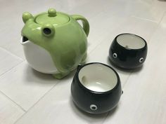 two black and white bowls sitting next to each other on the floor, one with a green frog face