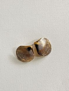 two seashells are sitting on a white surface, one is gold and the other is silver