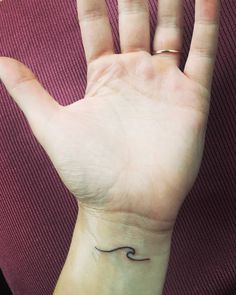 a woman's hand with a small wave tattoo on it