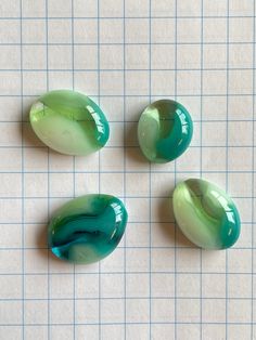 three green marbles sitting on top of a piece of white paper next to each other