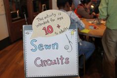 a sign that says sewn circuit's on it in front of some people