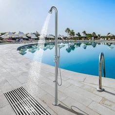 a large swimming pool with water spouting from it's sides and an open air shower head