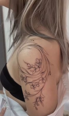 the back of a woman's shoulder with flowers and vines on her left arm