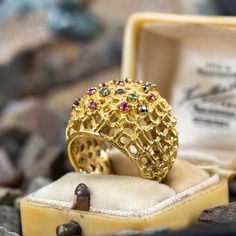 This striking circa 1970s ring features an organic design with open work details and is prong set with eight (8) round mixed cut rubies, five (5) round mixed cut emeralds and seven (7) round mixed cut sapphires. The ring measures 20.9mm at the top, rises 8.7mm above the finger, tapering to 7.0mm wide and 1.4mm thick at the base of the shank. This ring is currently a size 4.5. Yellow Gold Multi-stone Ruby Ring, Multi-stone Ruby Ring In Yellow Gold, Unique Multi-stone Ruby Ring In Yellow Gold, Fine Jewelry Multi-stone Dome Ring, Gold Multi-stone Emerald Open Ring, Gold Emerald Multi-stone Open Ring, Brand Presentation, Multi Gemstone Ring, Organic Design