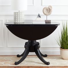 a black table with a white lamp on top and a potted plant next to it